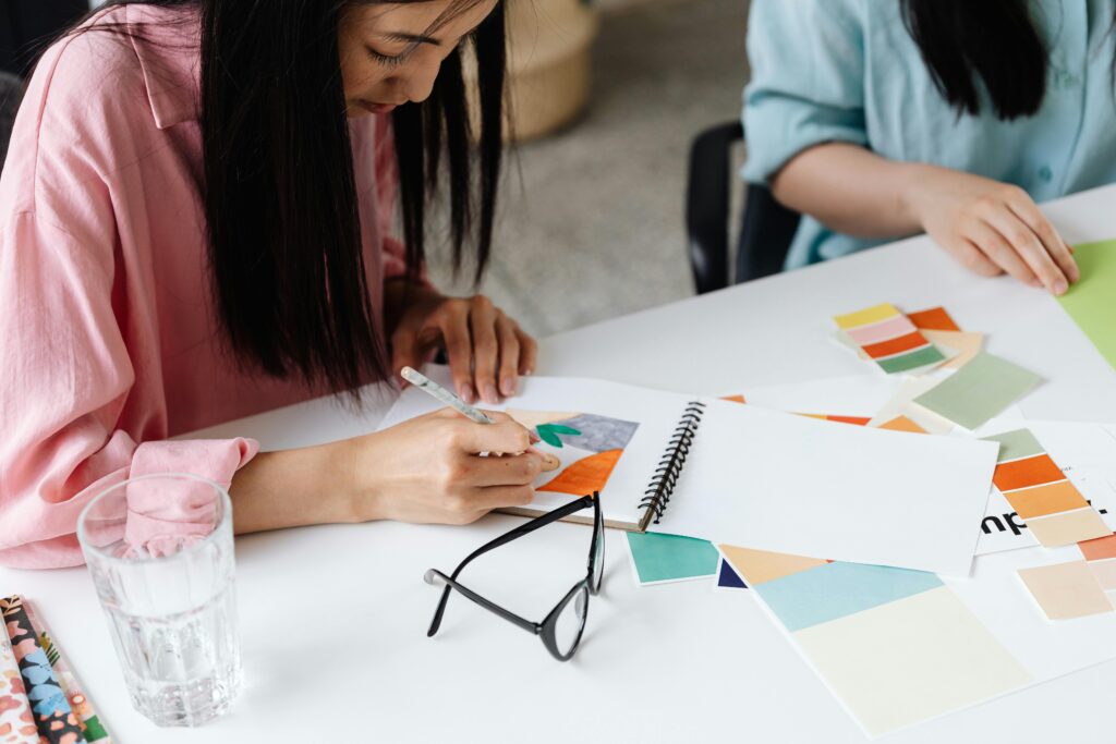 Women engaged in arts and crafts, creating colorful designs at a desk.